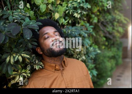 Young man standing with eyes closed near plants Stock Photo