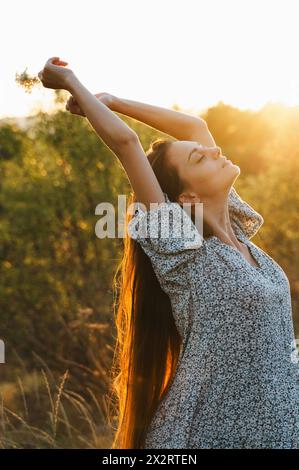 Beautiful woman stretching in field at sunset Stock Photo