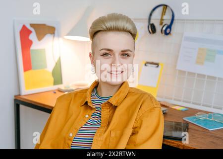 Smiling young woman sitting near desk at home Stock Photo