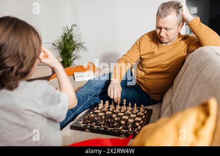 Father and son playing chess on sofa at home Stock Photo