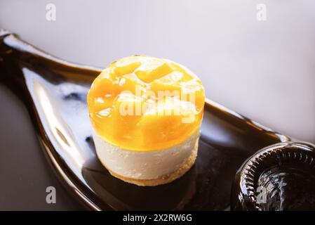 Mango tart soufflé cake on a lined plate made from a wine bottle on grey background Stock Photo