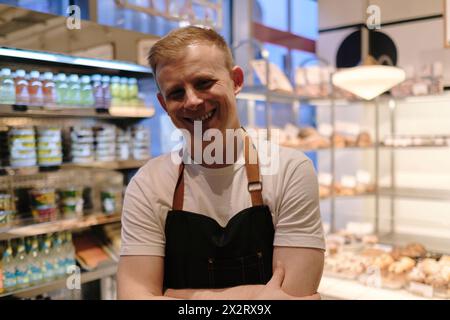 Happy baker standing with arms crossed in store Stock Photo