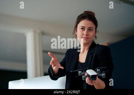Confident businesswoman holding drone gesturing at home office Stock Photo