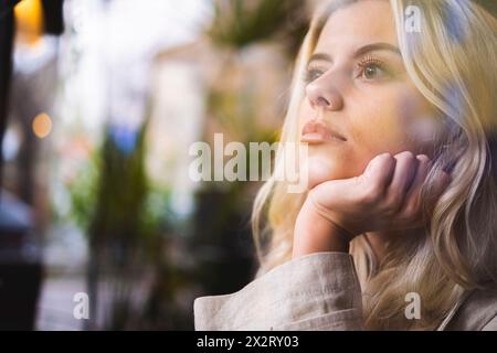 Thoughtful young woman seen through glass Stock Photo