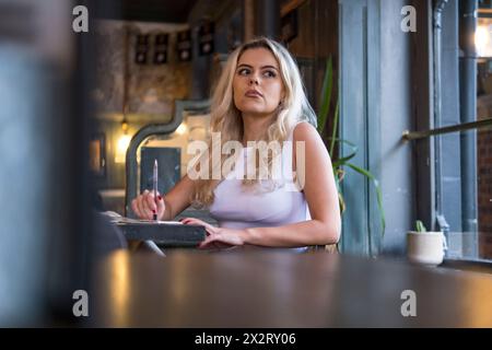Thoughtful young woman sitting at table in cafe Stock Photo