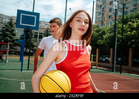 Basketball player walking with friend in background at school yard Stock Photo