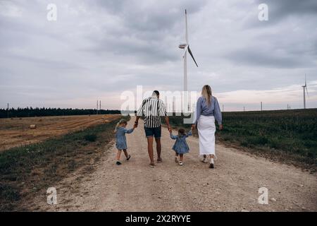Father and mother holding hands of daughters and walking on dirt road Stock Photo