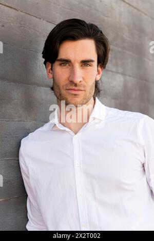 Confident young businessman leaning on wall Stock Photo