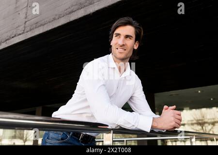 Smiling young businessman leaning on railing Stock Photo