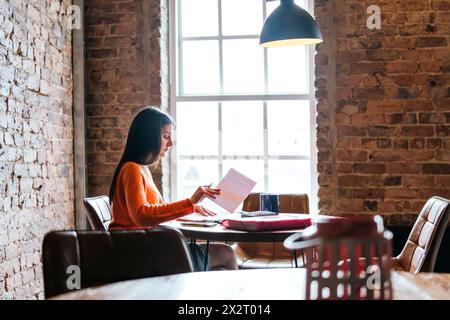 Young woman studying at restaurant Stock Photo