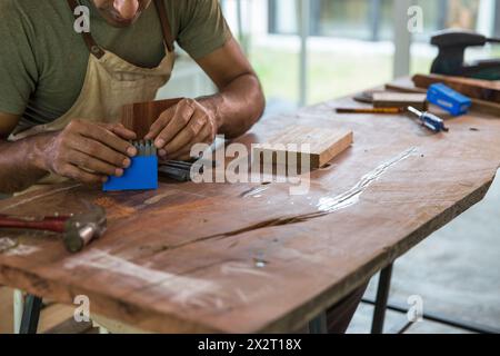 Carpenter using steel punch tool kit at workbench in woodshop Stock Photo