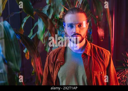 Man wearing smart glasses and standing near plants Stock Photo
