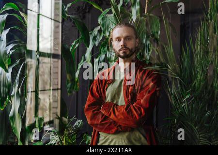 Man standing with arms crossed near plants Stock Photo