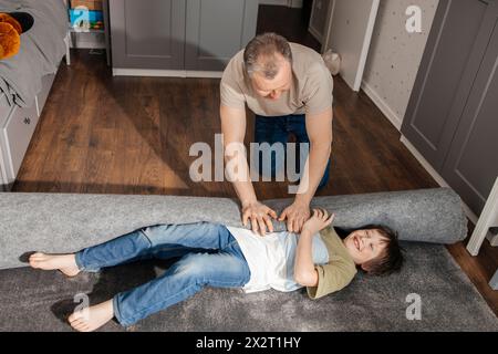 Father playing with son lying on carpet at home Stock Photo