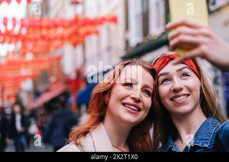 Smiling friends taking selfie through smart phone Stock Photo