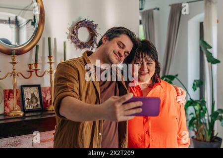 Smiling man taking selfie with mother at home Stock Photo