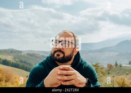 Bearded man with hands clasped wearing eyeglasses Stock Photo