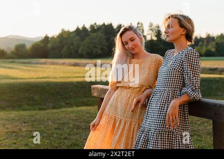 Thoughtful friends leaning on wooden railing in park Stock Photo