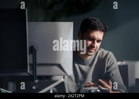 Businessman using mobile phone near desktop PC in office Stock Photo