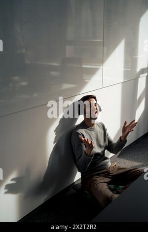 Cheerful mature businessman talking on headset and sitting near wall in office Stock Photo