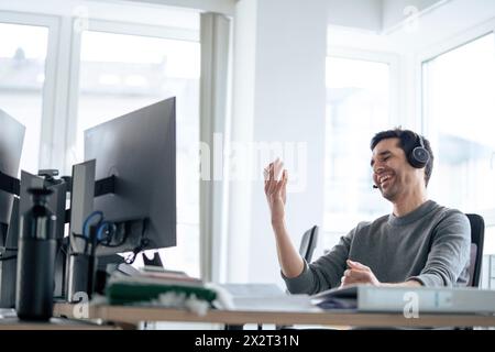 Happy businessman wearing headset and talking in office Stock Photo