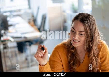 Happy businesswoman with felt tip pen in office Stock Photo