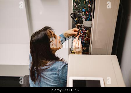 Female technician checking AC unit with screwdriver Stock Photo