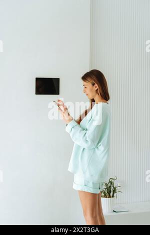 Woman operating home automation app through smart phone at home Stock Photo