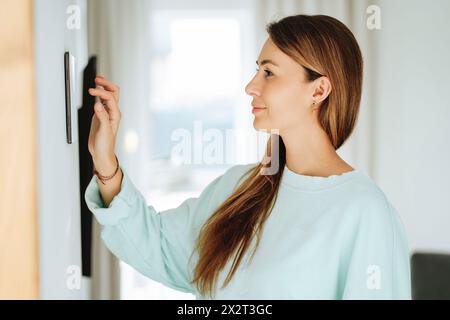 Woman with long hair using tablet PC mounted on wall at home Stock Photo