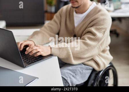 Businessman in wheelchair working on laptop at desk Stock Photo