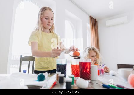 Sisters painting eggs for Easter at home Stock Photo