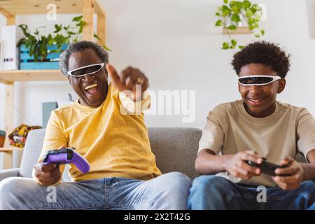 Cheerful grandfather and grandson playing video game at home Stock Photo
