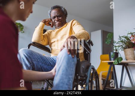 Doctor examining leg of senior man sitting in wheelchair Stock Photo