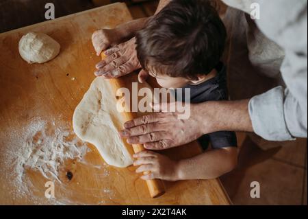 Son helping father in kitchen at home Stock Photo