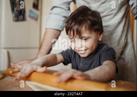 Smiling son helping father in kitchen at home Stock Photo