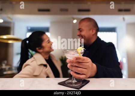 Couple talking to each other with cocktail at illuminated bar counter in restaurant Stock Photo