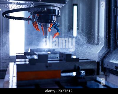 Computerized machine drilling metal object at factory Stock Photo