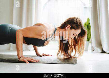 Determined woman doing push-ups at home Stock Photo