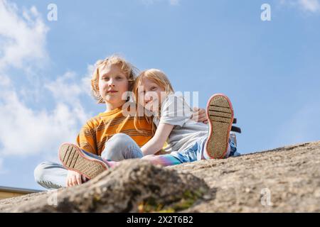 Boy sitting with sister on rock Stock Photo