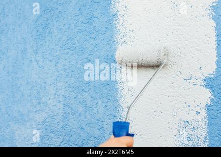 Hand of girl painting white color on wall using roller Stock Photo