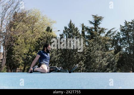 Athlete with artificial leg stretching on sports track Stock Photo