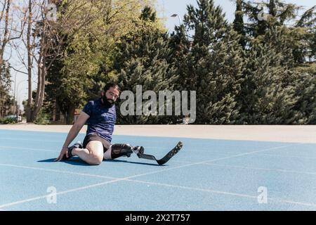 Athlete with prosthetic leg stretching on sports track Stock Photo