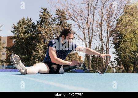Athlete with prosthetic leg stretching on track Stock Photo