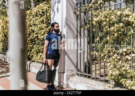 Athlete with prosthetic leg leaning on fence Stock Photo