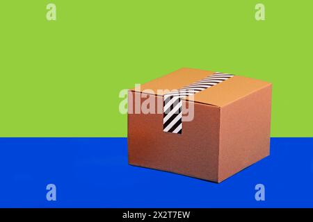 Taped cardboard box against green and blue background Stock Photo