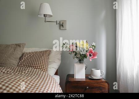 Spring interior still life. Blank vertical greeting card, invitation mockup. Elegant bedroom. Tulips, cherry tree blossoms bouquet in glass vase Stock Photo