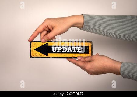 Update Concept. Pointing arrow with text in hands on white background. Stock Photo