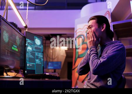 Excited hacker getting access granted while breaking into database server. Happy shocked young asian criminal hacking system successfully while doing illegal activities at night Stock Photo