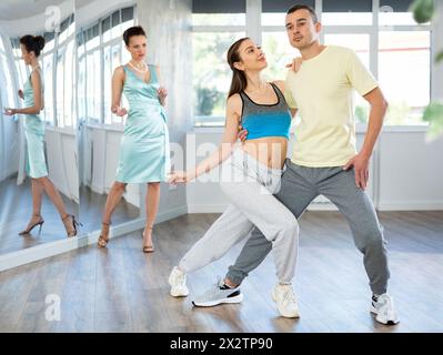 Couple practicing passionate tango guided by female dance instructor in studio Stock Photo
