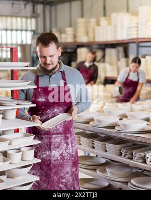 Ceramicist Examining Batch Of Slipcast Pottery In Ceramic Workshop